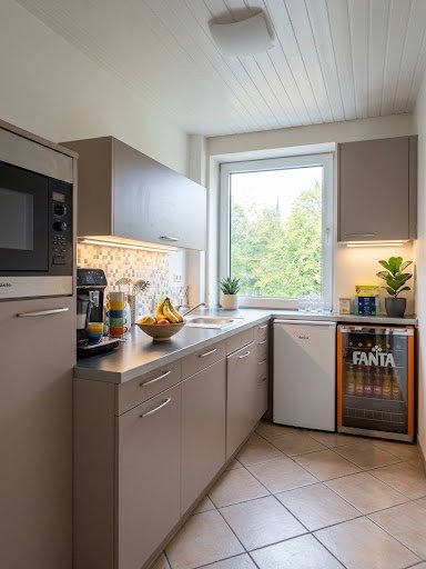 Kleine helle Küche bei Justa+ mit Kaffeemaschine, Obstschale und Getränkekühlschrank